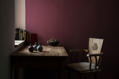 在涂有栗色漆的房间里，椅子旁边的桌子上放着三个花瓶